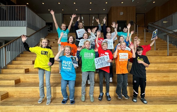 En gruppe barn med t-skjorter fra forskjellige TV-aksjoner hopper og jubler i en trapp.