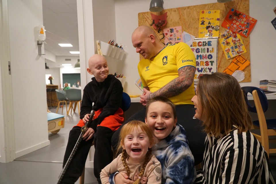 Familie smiler og omfavner hverandre i et hjemlig rom ved TrygFondens Familiehus i Århus.