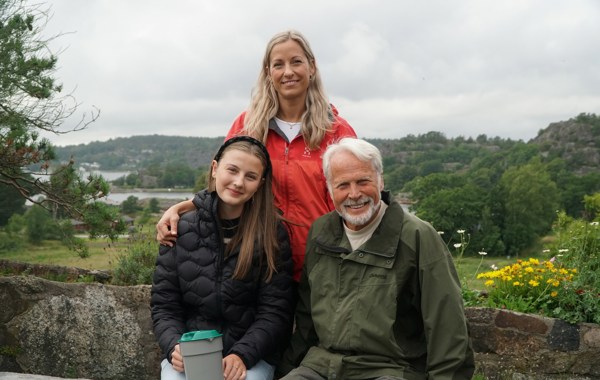 En eldre mann, en kvinne og ung jente samlet. Jenta har en bøsse i hånda. I bakgrunnen er det grønn natur.