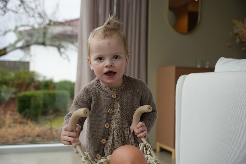 Liten blond jente som triller på en dukkevogn.