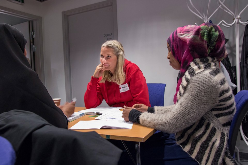 Kronprinsesse Mette-Marit i Tromsø i forbindelse med TV-aksjonen for Røde Kors i 2016. Hun sitter med to kvinner i hijab, og har på seg Røde Kors hettegenser.