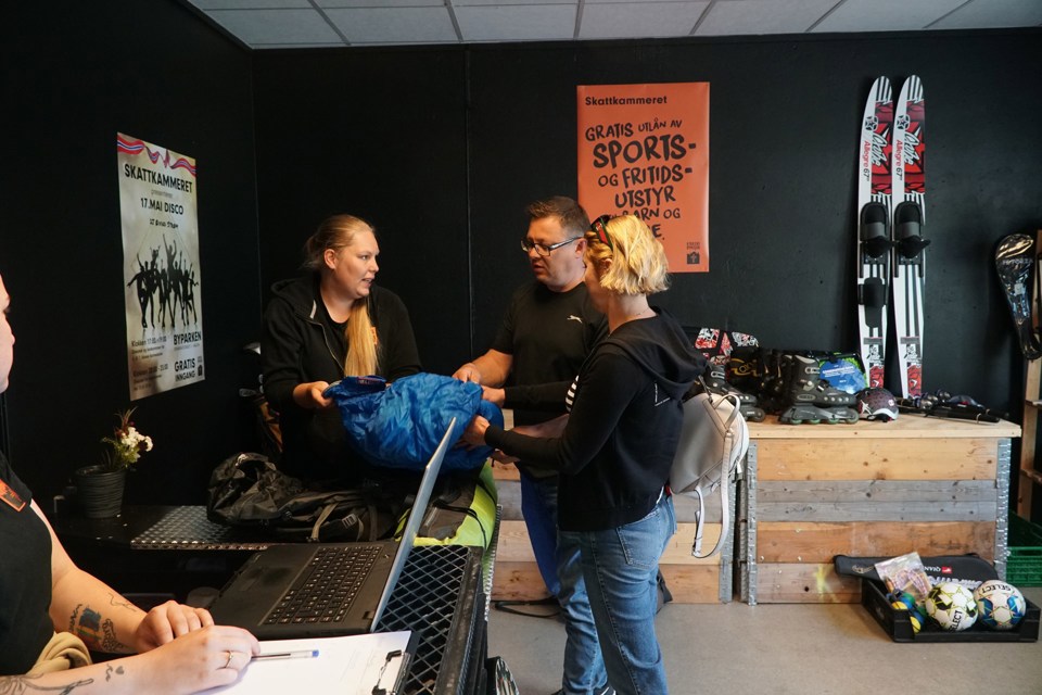 Tre mennesker som snakker sammen. I bakgrunn er det diverse sportsutstyr.