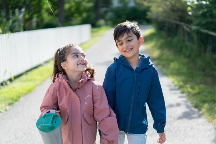 En jente og en gutt går med bøsse ute på en vei og smiler.