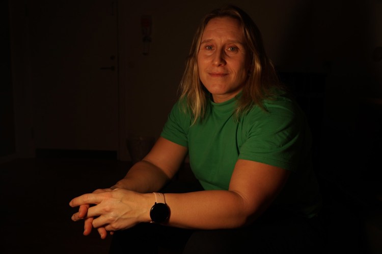 Kvinne med grønn tskjorte i mørkt rom