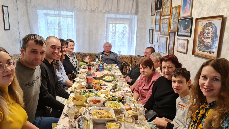 Mange mennesker sitter rundt et langt bord med mat. 
