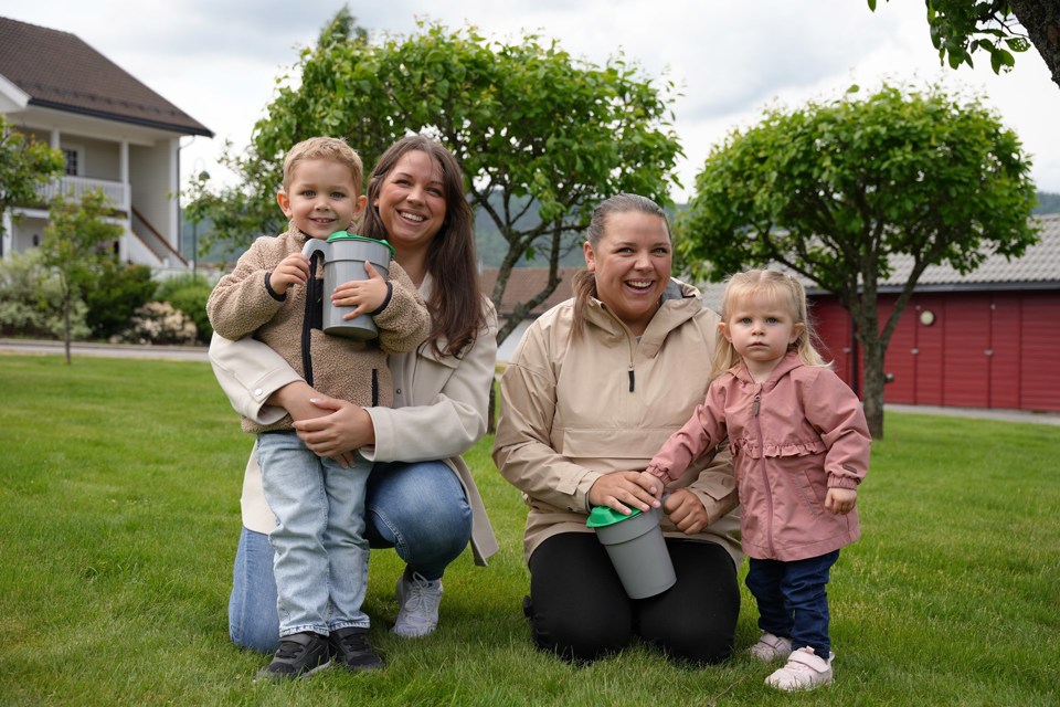 To mødre med hvert sitt barn sitter på en gressplen. 