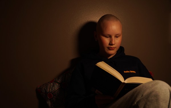 Ung kvinne uten hår leser en bok