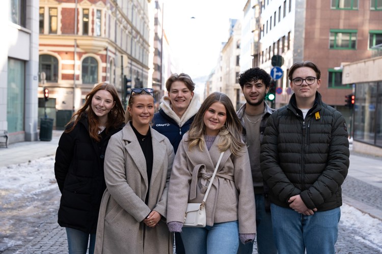 Tre unge kvinner og tre unge menn står samlet og smiler til kamera.