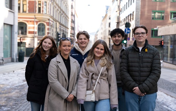 Tre unge kvinner og tre unge menn står samlet og smiler til kamera.