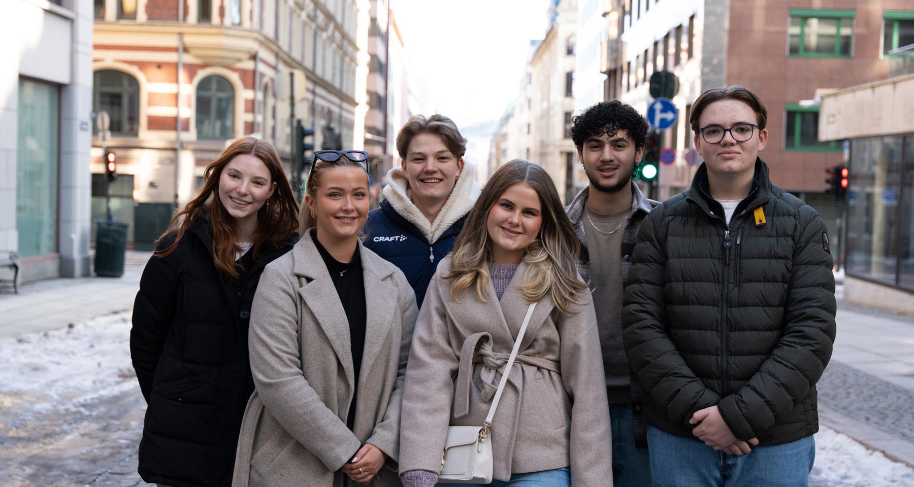 Tre unge kvinner og tre unge menn står samlet og smiler til kamera.