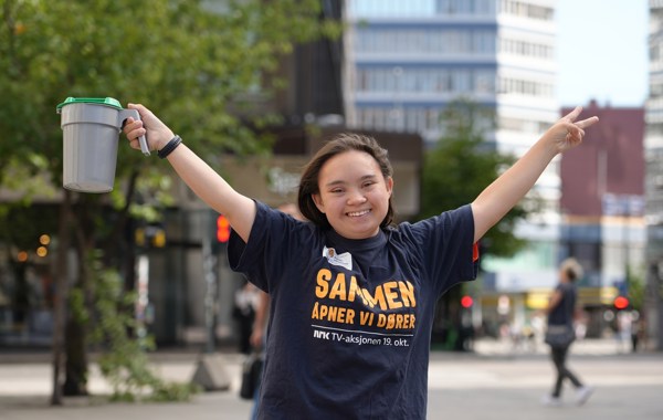 Smilende jente holder hendene i været og har en bøsse i den ene hånda. 