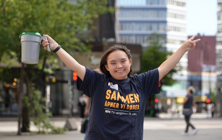 Smilende jente holder hendene i været og har en bøsse i den ene hånda. 