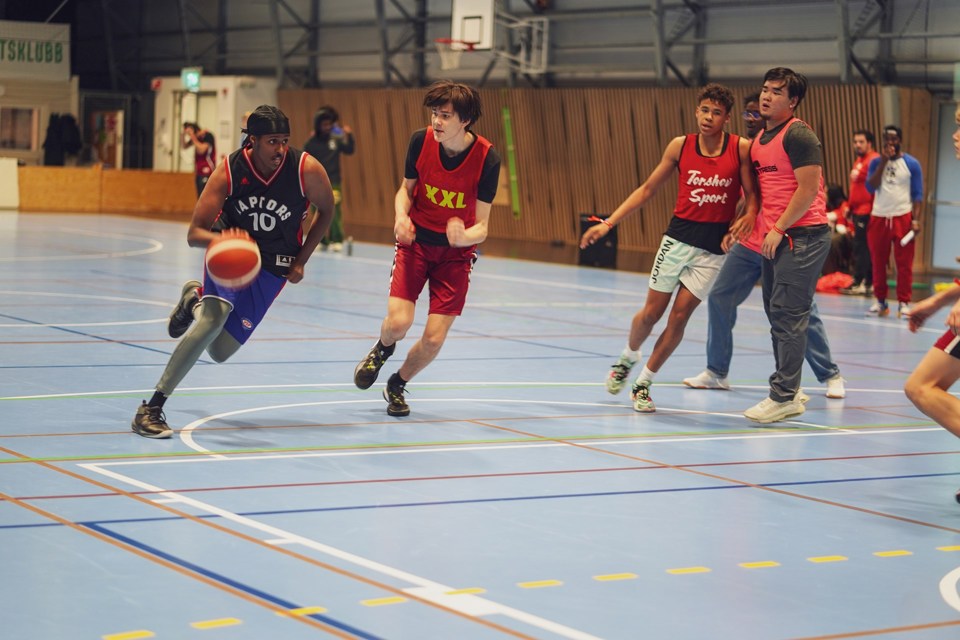 Ungdom som spiller basketball. En gutt har ballen, mens tre andre står rundt.