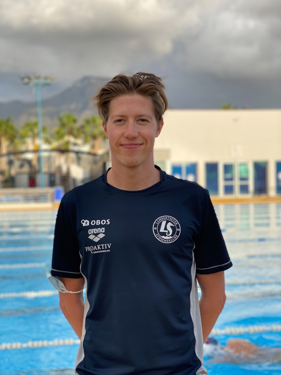 OL-deltaker Henrik Christiansen står foran et svømmebasseng.