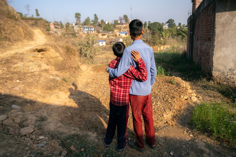 To unge gutter holder rundt hverandre, vi ser dem bakfra. 