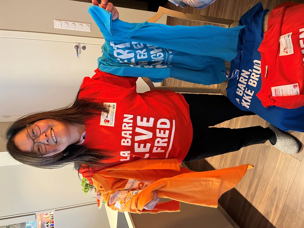 Kvinne viser frem forskjellige t-skjorter fra TV-aksjonen.