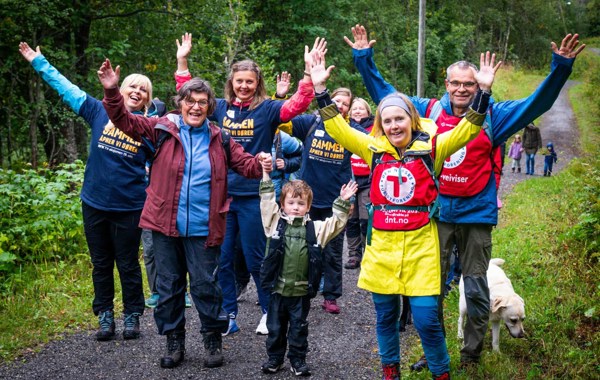 En gruppe mennesker er på tur og løfter armene mens de smiler. 