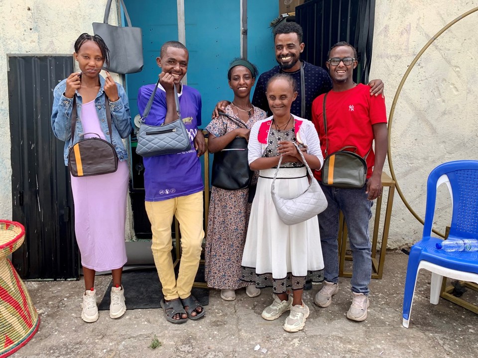 Seks mennesker i Etiopia viser frem vesker og smiler. 