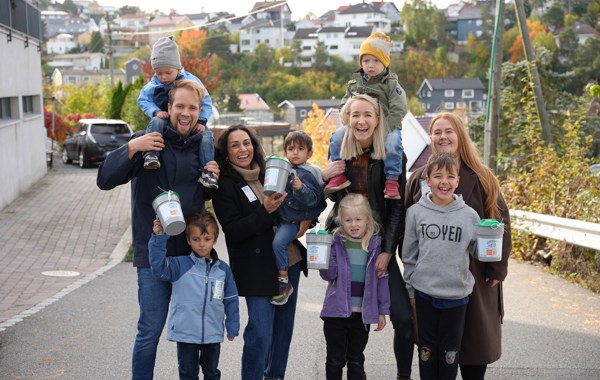 Fire voksne og seks barn smilende med bøsser i henda.