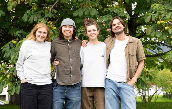 To kvinner og to menn som holder rundt hverandre og står foran et stort, grønt tre