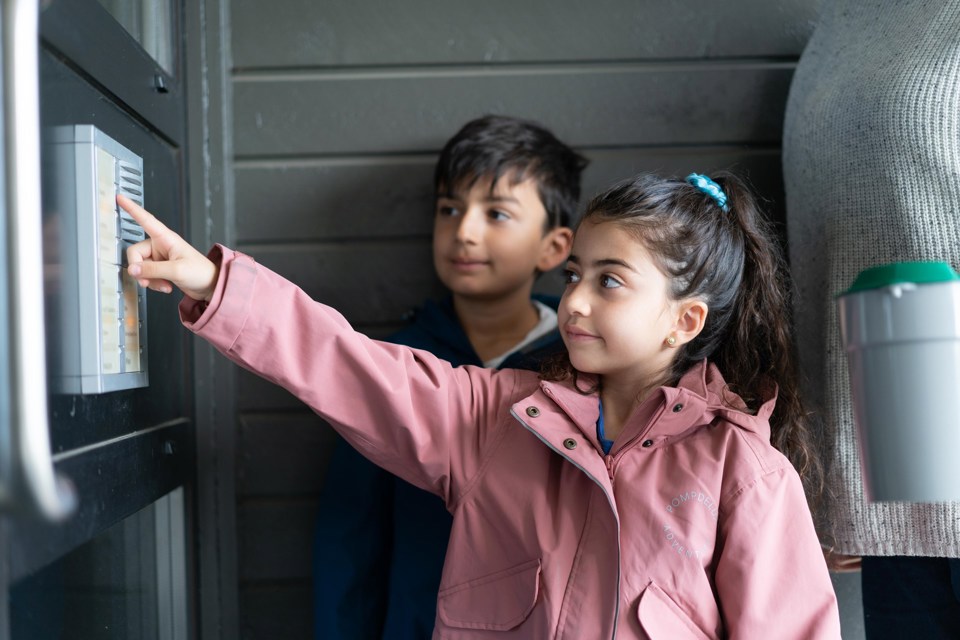 To barn ringer på en dør, mens en voksen står bak og holder en bøsse.