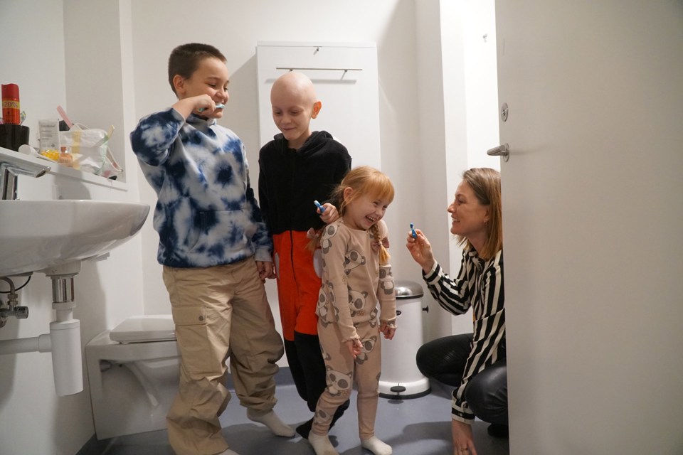 Barna smiler og ler mens de pusser tennene på badet. 