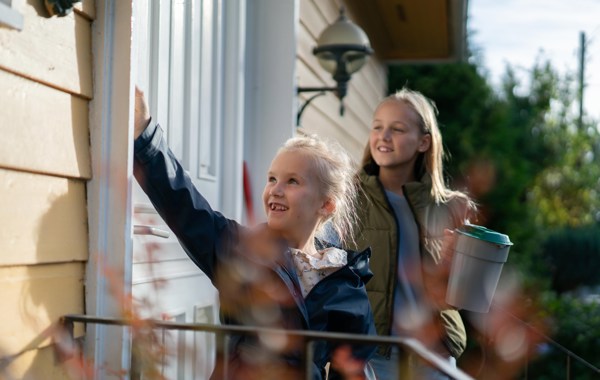 To unge jenter som banker på en dør med bøsse i hånda.