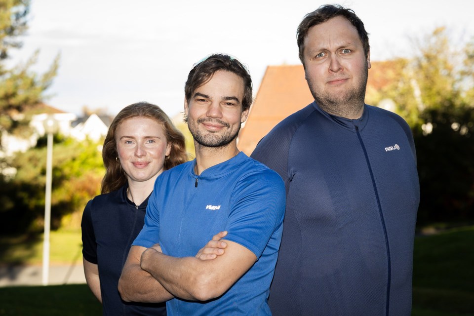 To menn og en kvinne i treningsklær smiler til kamera.