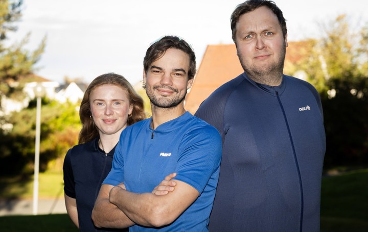 To menn og en kvinne i treningsklær smiler til kamera.