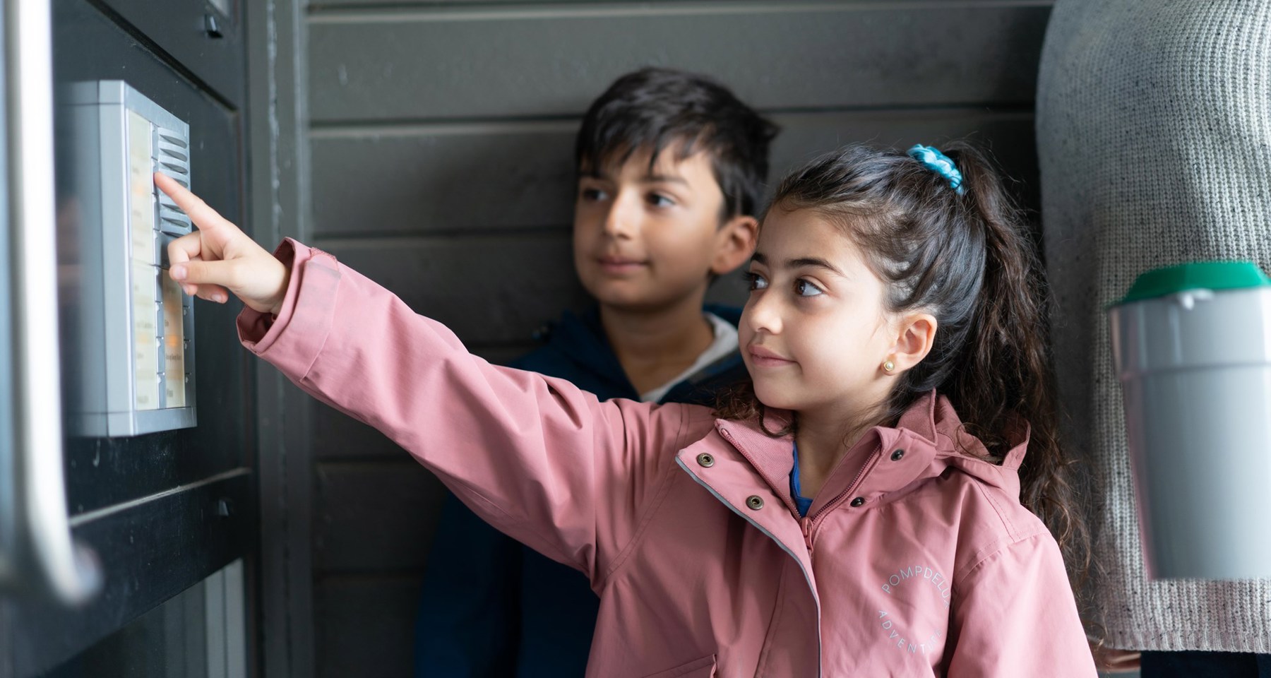 To barn ringer på en dør, mens en voksen står bak og holder en bøsse.