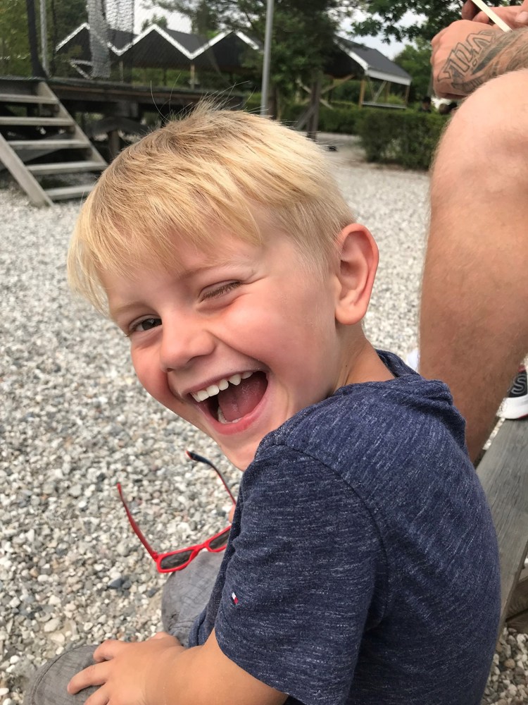 Blond gutt som smiler bredt.