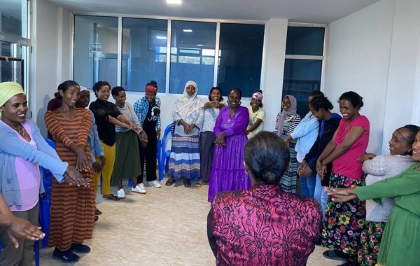 En grupper kvinner står i ring med armene utstrakt og smil om munnen i Etiopia. 