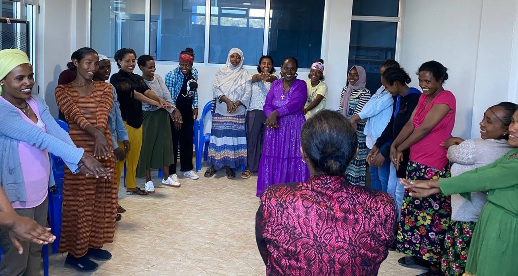 En grupper kvinner står i ring med armene utstrakt og smil om munnen i Etiopia. 