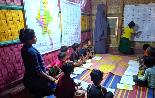 Barn sitter på gulvet og har undervisning.