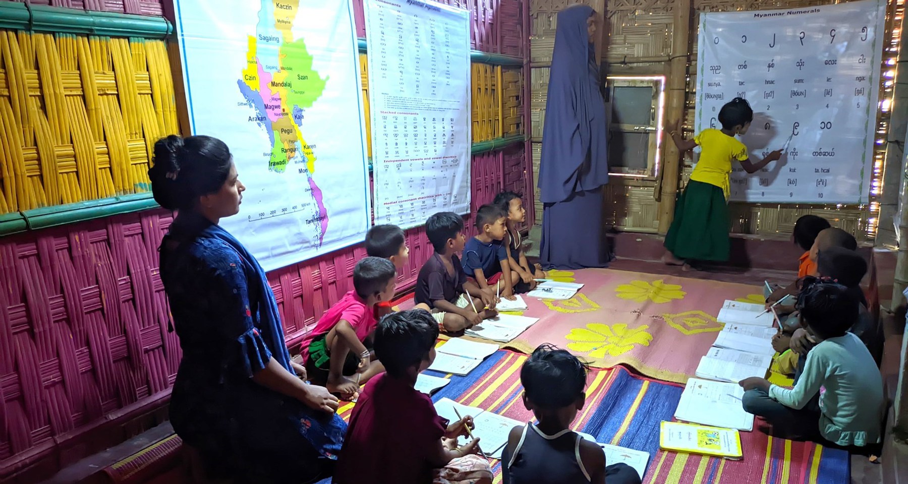 Barn sitter på gulvet og har undervisning.